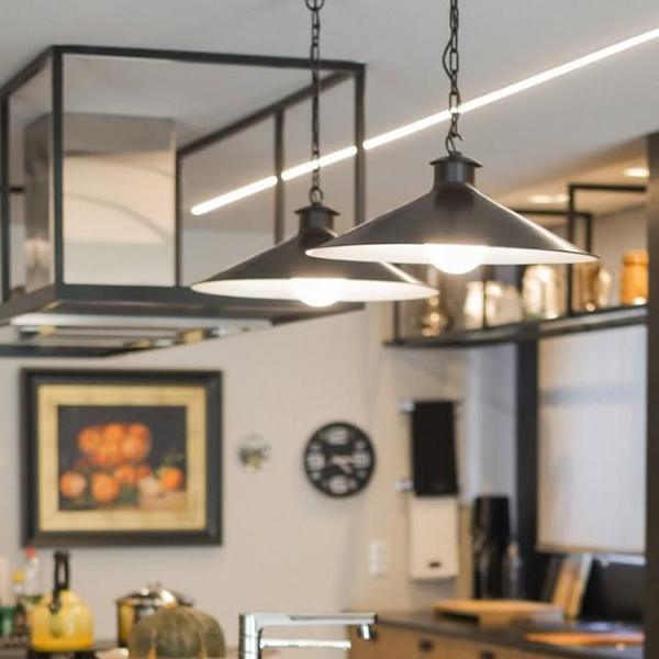 Prateleira suspensa em metal com luminárias pendentes e armários sob medida